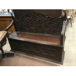 LATE VICTORIAN CARVED OAK HALL SETTLE IN THE ANGLO-INDIAN MANNER the shaped arched back panel