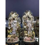 PAIR OF LARGE GLASS CLOCHES ON WOODEN STANDS containing ceramic figures surrounded by artificial