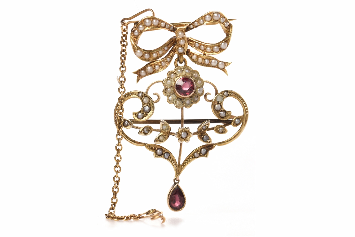 EDWARDIAN NINE CARAT GOLD BROOCH PENDANT of openwork form and set with seed pearls and two garnets,