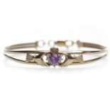 NINE CARAT GOLD CLADDAGH BANGLE set with a purple heart shaped stone,