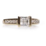 EIGHTEEN CARAT GOLD CZ DRESS RING set with a single central square CZ on channel set CZ shoulders,