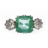 IMPRESSIVE EMERALD AND DIAMOND THREE STONE RING set with a central emerald cut emerald 8.5x8.4x4.