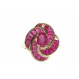 NINE CARAT GOLD RUBY CLUSTER RING set with a central oval ruby 7mm long with radiating curving rows