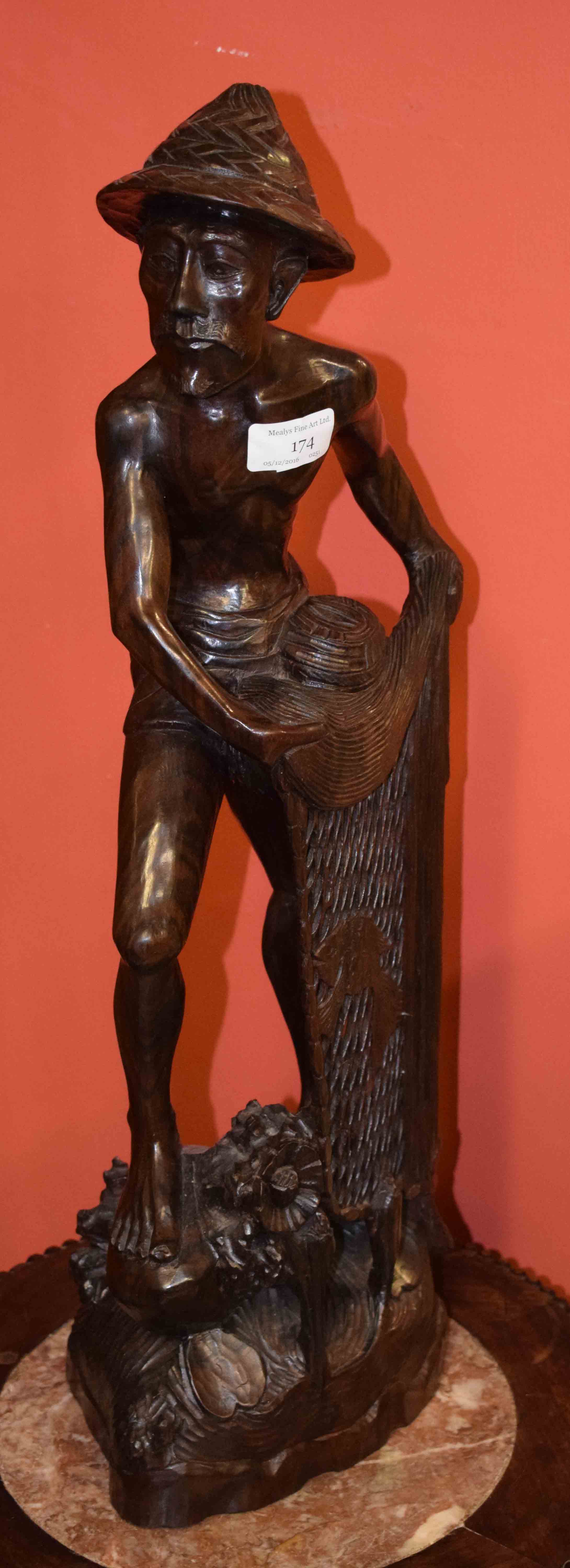 A BALINESE CARVED HARDWOOD FIGURE, modelled with a fisherman holding a net, 23.5'' (60cm) high. (1)