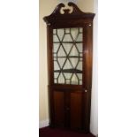 A MAHOGANY CORNER CABINET, in the George III style, with fret cut swan neck pediment, and dentil