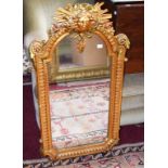 A MODERN GILT PIER MIRROR, crested with a classical mask amongst foliage, above an arched mirror