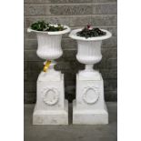 TWO SIMILAR CAST IRON GARDEN URNS AND STANDS
