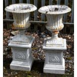 A PAIR OF HEAVY CAST IRON GARDEN URNS, each with half-fluted and reeded body, on a square fluted