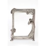 AN UNUSUAL ART NOUVEAU POLISHED PEWTER TABLE MIRROR, modelled with a woman with one hand aloft and