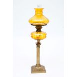 A LATE VICTORIAN BRASS OIL LAMP, with amber glass reservoir and shade, the reeded column with