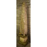 A COMPOSITION LIMESTONE GARDEN OBELISK, with paneled sides, raised on four ball feet, and a three