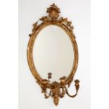 A 19TH CENTURY OVAL GILT AND GESSO GIRANDOLE, with shell and oval crest, above a mirror plate, in