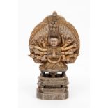 A CARVED SOAPSTONE FIGURE OF THE BUDDHA, seated on a two-tier stand, with many hands, supported by