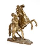 A SMALL GILT BRONZE EQUESTRIAN GROUP, after Coustou, modelled with Marley horse and groom, on rugged