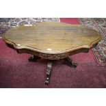 AN OVAL SERPENTINE SHAPED WALNUT VICTORIAN STYLE OCCASIONAL TABLE, raised on quadruple carved pod,