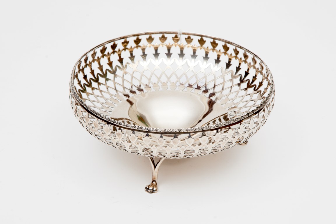 A PIERCED SILVER BASKET BOWL, Birmingham 1923, with leaf cast edge and raised on three paw feet,