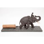 A LARGE CARVED WOODEN GROUP, modelled with young Thai man seated on an elephant, pulling a log, with