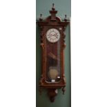 A VICTORIAN FIGURED WALNUT VIENNA STYLE WALL CLOCK, with arched pediment and three urn finials,