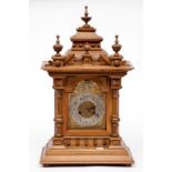 A WALNUT CASED MANTEL CLOCK, early 20th century, of architectural design, with four urn finials