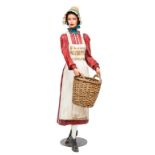 A VERY UNUSUAL AND RARE LIFE SIZE MODEL OF A WOMAN WITH BONNET AND SHOP APRON HOLDING A BASKET