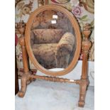 A VICTORIAN OVAL WALNUT DRESSING TABLE MIRROR, with fluted supports, and urn finials, raised on four