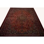 A LARGE BURGUNDY GROUND PERSIAN MASHAD CARPET