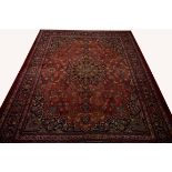 A LARGE BURGUNDY GROUND PERSIAN MASHAD CARPET