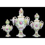 A GRADUATED SET OF THREE GERMAN PORCELAIN FLORAL ENCRUSTED VASES AND COVERS IN 18TH CENTURY STYLE,