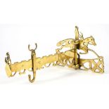 A VICTORIAN PIERCED BRASS CHIMNEY CRAME, THE WALL PLATE IN THE FORM OF A MOUNTED RIDER, ARM 24CM L