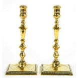 A PAIR OF BRASS CANDLESTICKS ON GADROONED SQUARE FOOT, 26CM H