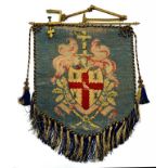 A VICTORIAN ARMORIAL WOOLWORK FIRESCREEN ON LACQUERED BRASS DOUBLE HINGED BRACKET WITH CLAMP, BANNER