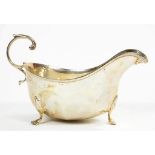 A GEORGE V SILVER SAUCE BOAT WITH FLYING SCROLL HANDLE AND PANEL SIDES, ON THREE HOOF FEET, 14CM