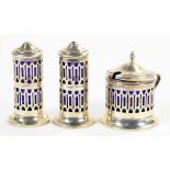 A GEORGE V PIERCED SILVER THREE PIECE CONDIMENT SET OF CYLINDRICAL FORM WITH BLUE GLASS LINERS, SALT