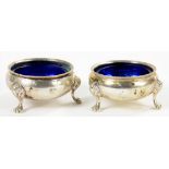 A PAIR OF VICTORIAN SILVER SALT CELLARS ON THREE PAW FEET, BLUE GLASS LINERS, 6.5CM DIAM, LONDON