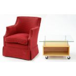 A RED UPHOLSTERED TUB CHAIR AND A MODERN GLASS TOPPED COFFEE TABLE