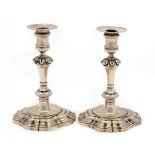 TWO GEORGE II SILVER CANDLESTICKS crested and a pair of later nozzles crested to match, 17.5cm h,