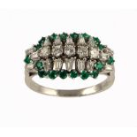 AN EMERALD AND DIAMOND RING with round, baguette and trapeze cut diamonds encircled by emeralds,