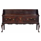 AN OAK DRESSER, SECOND HALF 18TH CENTURY fitted with three moulded drawers, the sides panelled, on