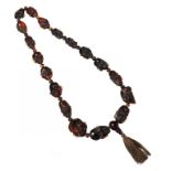 A NECKLACE OF 19 ROOT AMBER BEADS carved as human heads, 103.9g