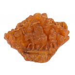 A CHINESE AMBER CARVING of a sage riding on a donkey attended by a boy, the reverse with prunus, 7cm