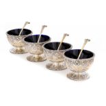 A SET OF FOUR VICTORIAN SILVER SALT CELLARS embossed with masks and strapwork, blue glass liners,