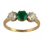 AN EMERALD AND DIAMOND RING the step cut hexagonal emerald flanked by old cut cushion shaped