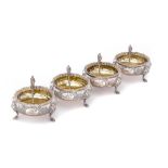 A SET OF FOUR VICTORIAN SILVER SALT CELLARS crisply chased with roses, 7.5cm diam and a set of