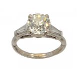 A DIAMOND RING with round old cut diamond, a trapeze cut diamond to each shoulder, in white gold,
