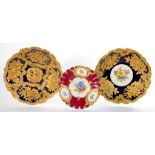 THREE MEISSEN MOULDED COBALT OR CLARET GROUND DISHES PAINTED WITH FLOWERS AND RICHLY GILT, 31CM DIAM