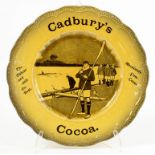 ADVERTISING. A RIDGWAYS AMBER GLAZED EARTHENWARE CADBURYS COCOA PLATE, PAINTED IN SEPIA WITH ROWERS,