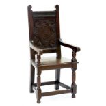 A 20TH CENTURY CARVED OAK DALES CHAIR WITH PANELLED BACK AND BOARDED SEAT