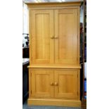 A MODERN LIGHT WAXED OAK CUPBOARD ENCLOSED BY TWO PAIRS OF PANELLED DOORS, 104CM W