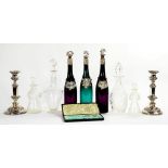 A CASED PAIR OF VICTORIAN PLATED GRAPE SHEARS, THREE GREEN OR PURPLE GLASS SPIRIT DECANTERS WITH