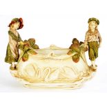 A ROYAL DUX SWAN JARDINIERE WITH BOY AND GIRL FIGURAL HANDLES, 27CM H, MARK IMPRESSED ON A PINK